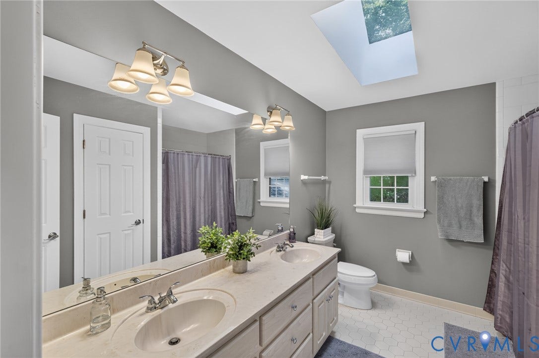 12800 Leffingwell Court, Henrico, VA 23233 Dual vanity with undermount sinks, full-width wall mirror, skylight, window with roller shade, and hexagonal floor tiling