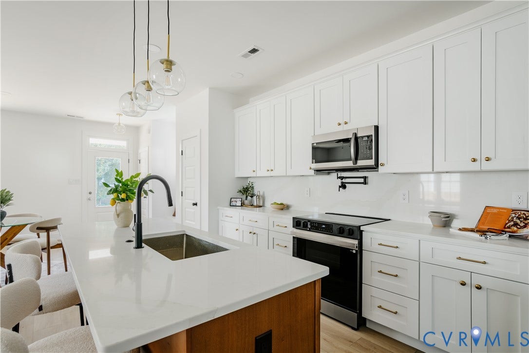 3106 Groveland Avenue, Richmond, VA 23222 Modern kitchen with white cabinetry, stainless steel appliances, a center island with sink, and pendulum lighting