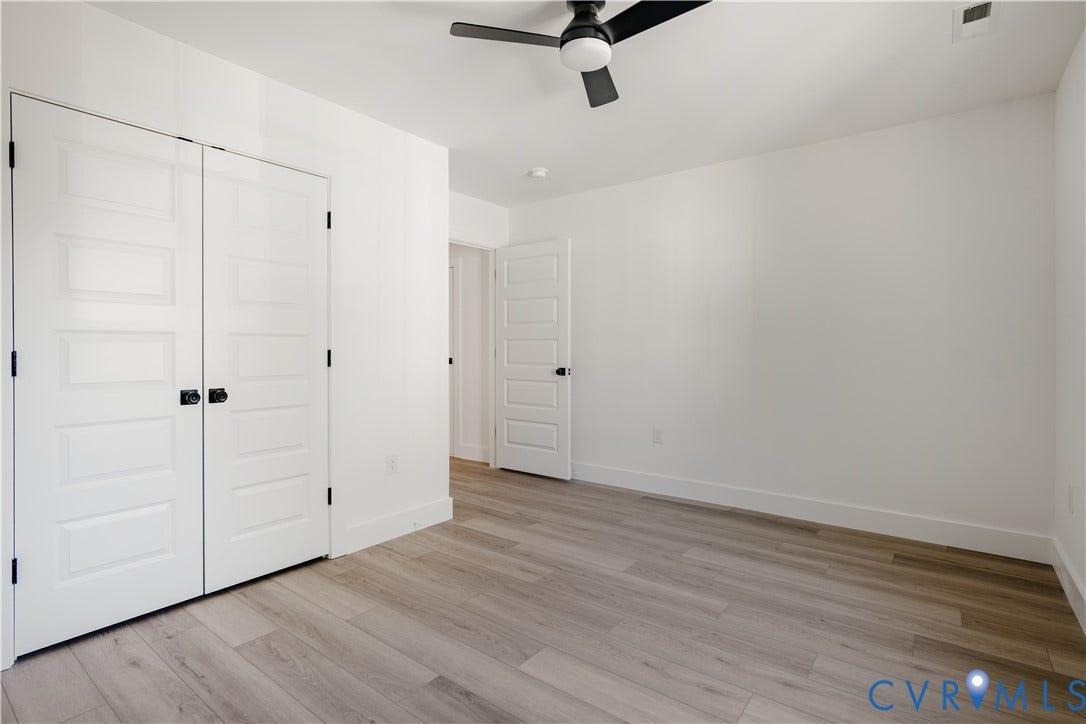 3106 Groveland Avenue, Richmond, VA 23222 Wood-finish flooring throughout, white paneled doors with black hardware, white walls, and a ceiling fan with integrated lighting