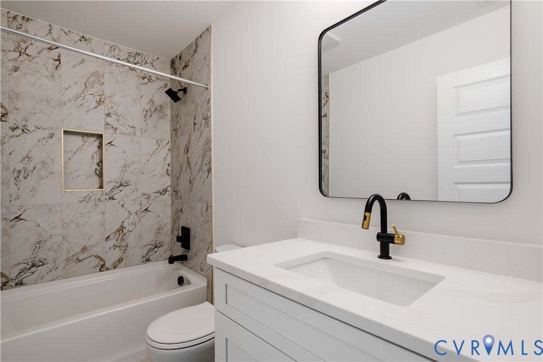 3106 Groveland Avenue, Richmond, VA 23222 White vanity with an integrated rectangular sink, matte black and brass-tone faucet, and a black-framed mirror