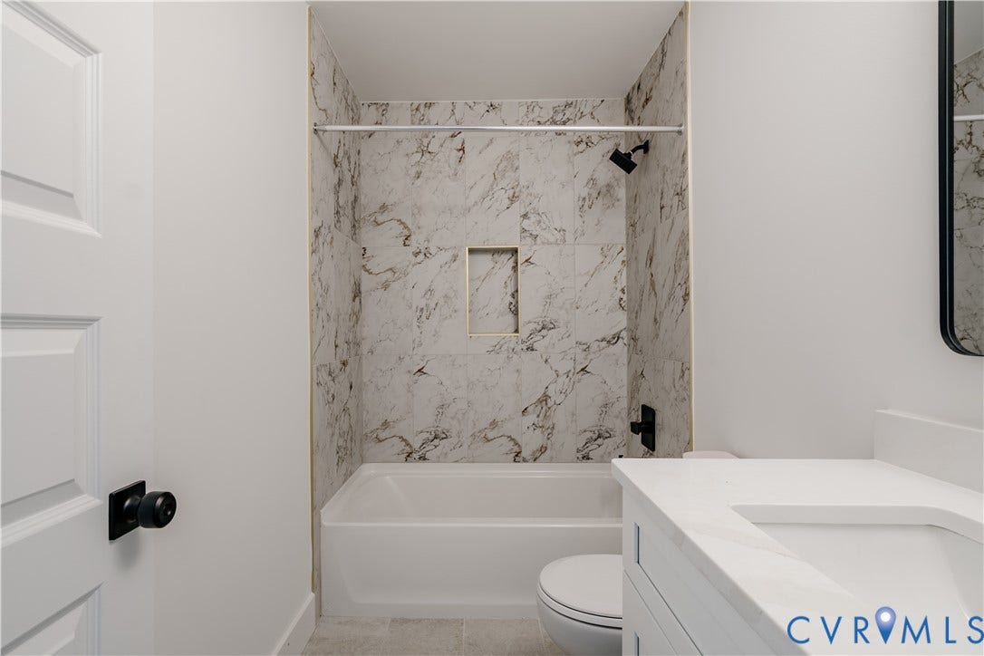 3106 Groveland Avenue, Richmond, VA 23222 Modern bathroom featuring a white vanity with an integrated sink, a white tub, and marble-look shower surround with a recessed niche