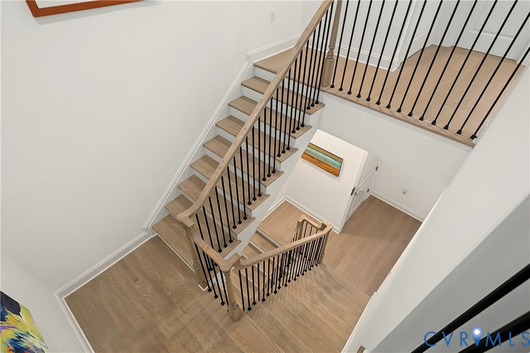 Multi-level staircase featuring wood-finish treads and risers, black metal balusters, and a wood-finish handrail