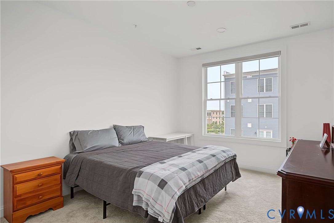 Recessed lighting, large window with blinds, and neutral carpet flooring