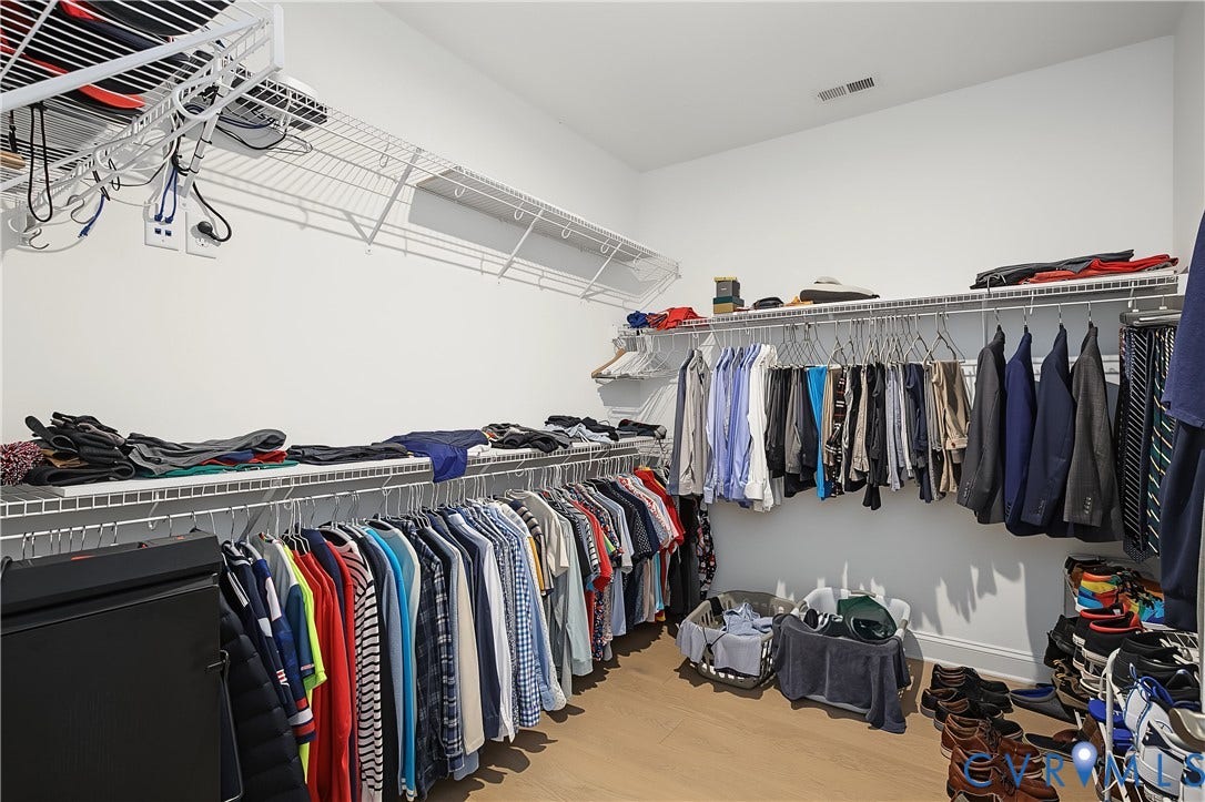 Primary Walk-in closet featuring extensive wire shelving, multiple hanging rods, and light wood-finish flooring