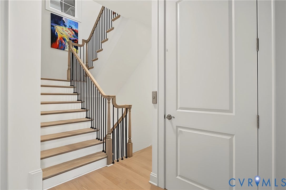 3rd Level Elevator Access, Hardwood flooring, wood-finish staircase with black iron spindles, white paneled doors, and a transom window