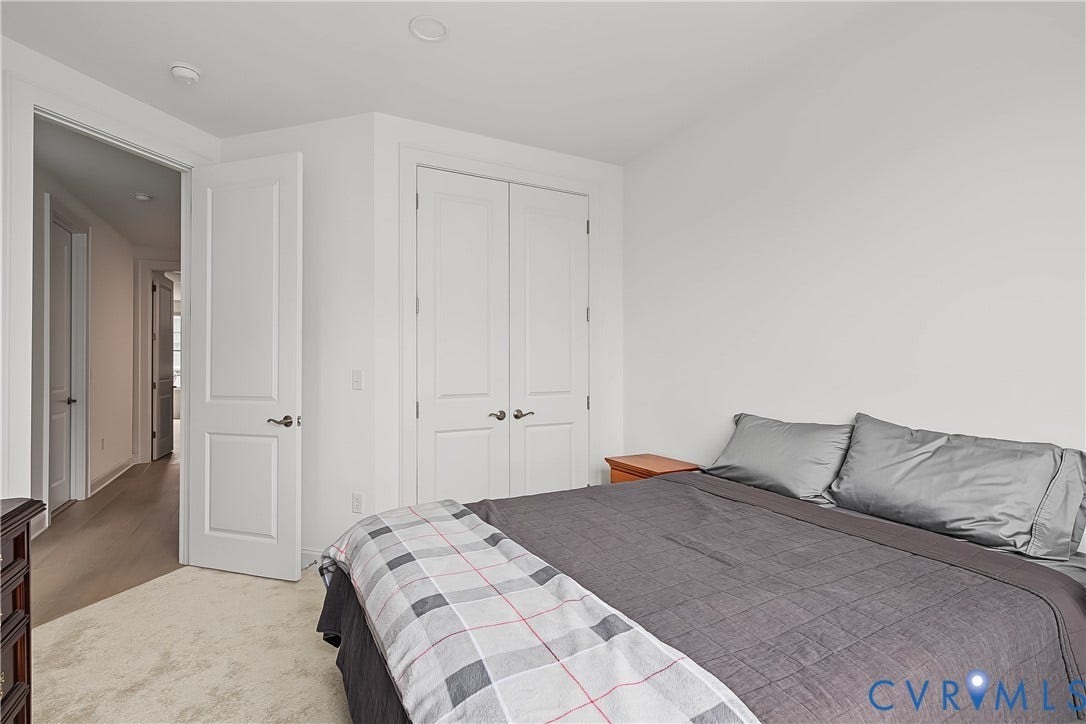 White interior doors, recessed ceiling lighting, light-toned wall-to-wall carpeting, and light wood-finish flooring in the hallway