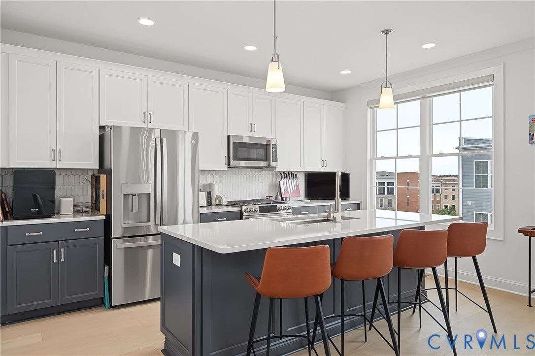 Kitchen featuring white upper cabinetry, dark lower cabinetry, stainless steel appliances, a center island with a light-colored countertop, and recessed lighting