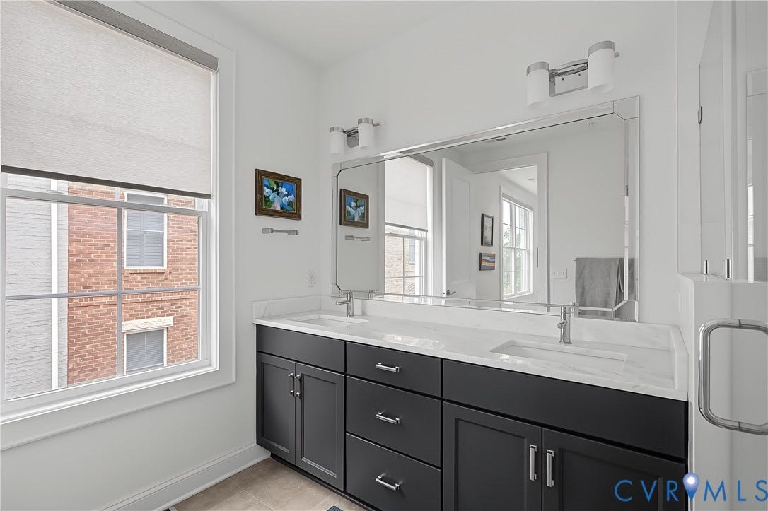 Dual vanity with undermount sinks, white countertop, and dark cabinetry
