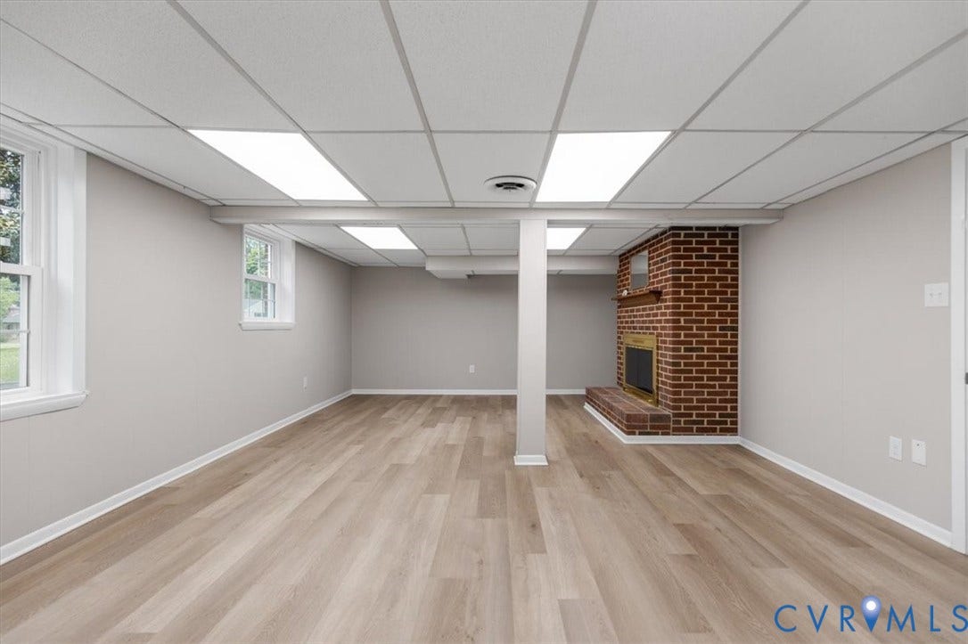 3308 Sylvania Road, Chesterfield, VA 23831 Wood-finish flooring with light gray walls, a brick fireplace with a wood mantle, and multiple egress windows