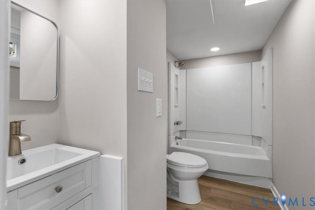 3308 Sylvania Road, Chesterfield, VA 23831 Contemporary bathroom featuring a white vanity with a basin sink, brushed nickel faucet, wall-mounted mirror, and wood-finish flooring