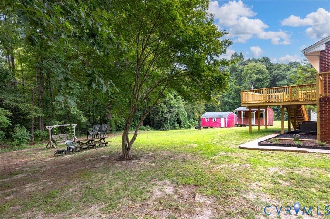 3308 Sylvania Road, Chesterfield, VA 23831 Expansive backyard with a manicured lawn, a large wood deck, and two red storage sheds
