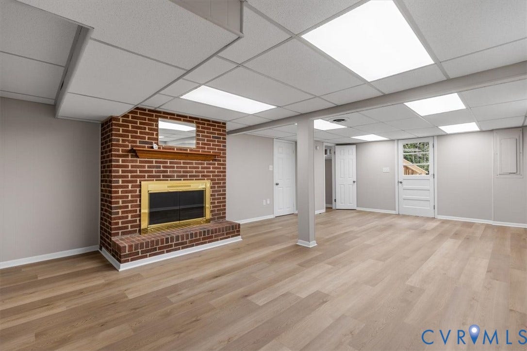 3308 Sylvania Road, Chesterfield, VA 23831 Expansive finished room featuring a brick fireplace with a brass-trim insert, wood-finish flooring, and recessed panel doors