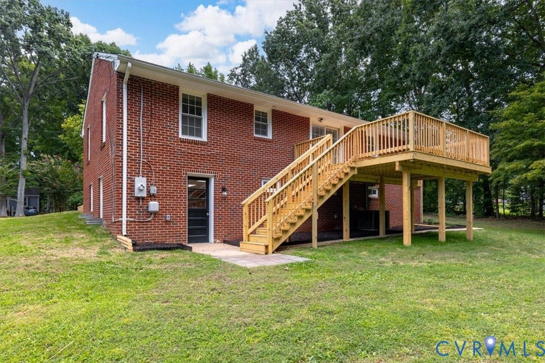 3308 Sylvania Road, Chesterfield, VA 23831 Red brick exterior with multiple windows, featuring a ground-level door with exterior lighting and a wood deck with stairs leading to a spacious elevated platform