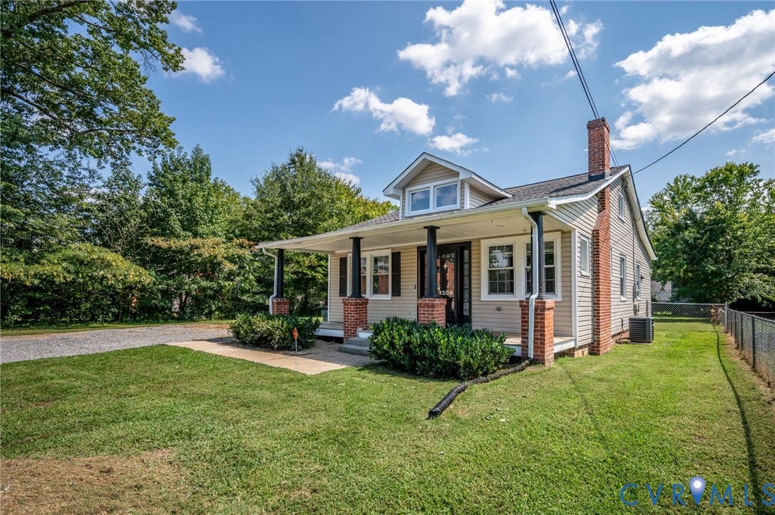 Home exterior featuring a covered porch with brick columns, dormer window, and a brick chimney