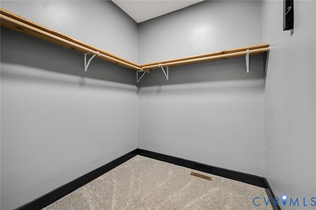 Neutral gray wall paint, dark trim, light-toned carpet, and a wood closet system