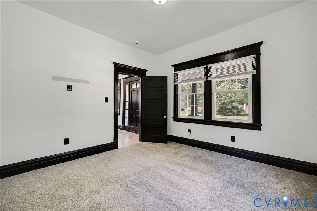 Light-colored carpeting with high ceilings, featuring dark trim work