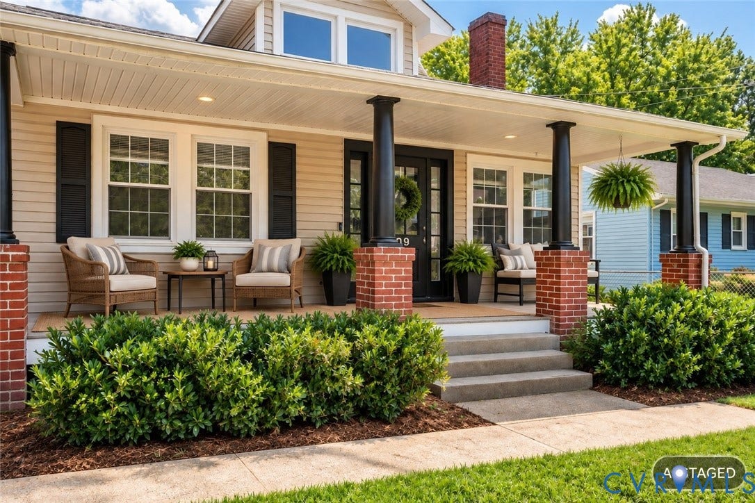 Covered porch with brick piers and black columns, featuring a black front door with sidelights, and exterior siding
