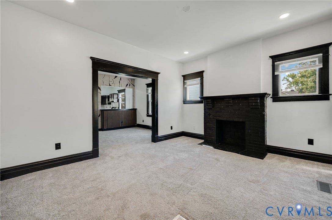 Bright interior with recessed lighting, light-toned carpeting, black trim, and a black brick fireplace