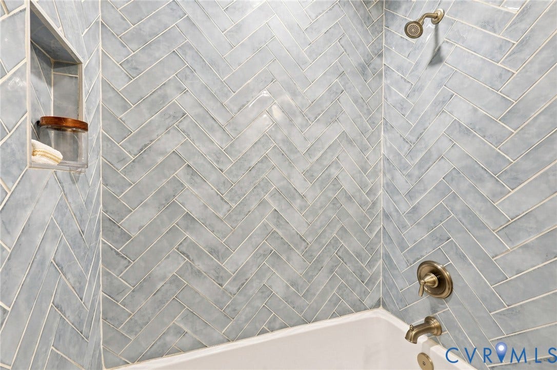 3221 Clintwood Road, Midlothian, VA 23112 Bathtub and shower combination featuring herringbone tile, built-in shower niche, and bronze fixtures