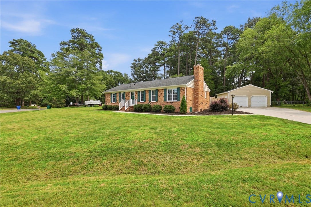 3221 Clintwood Road, Midlothian, VA 23112 Brick exterior with a prominent chimney, a detached two-car garage, and mature trees surrounding the property