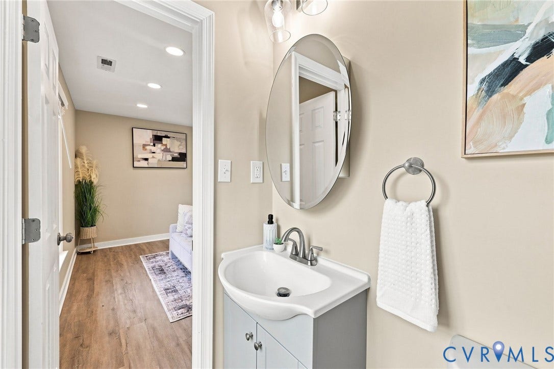 3221 Clintwood Road, Midlothian, VA 23112 Vanity with integrated sink, oval mirror, stainless steel faucet, and recessed lighting
