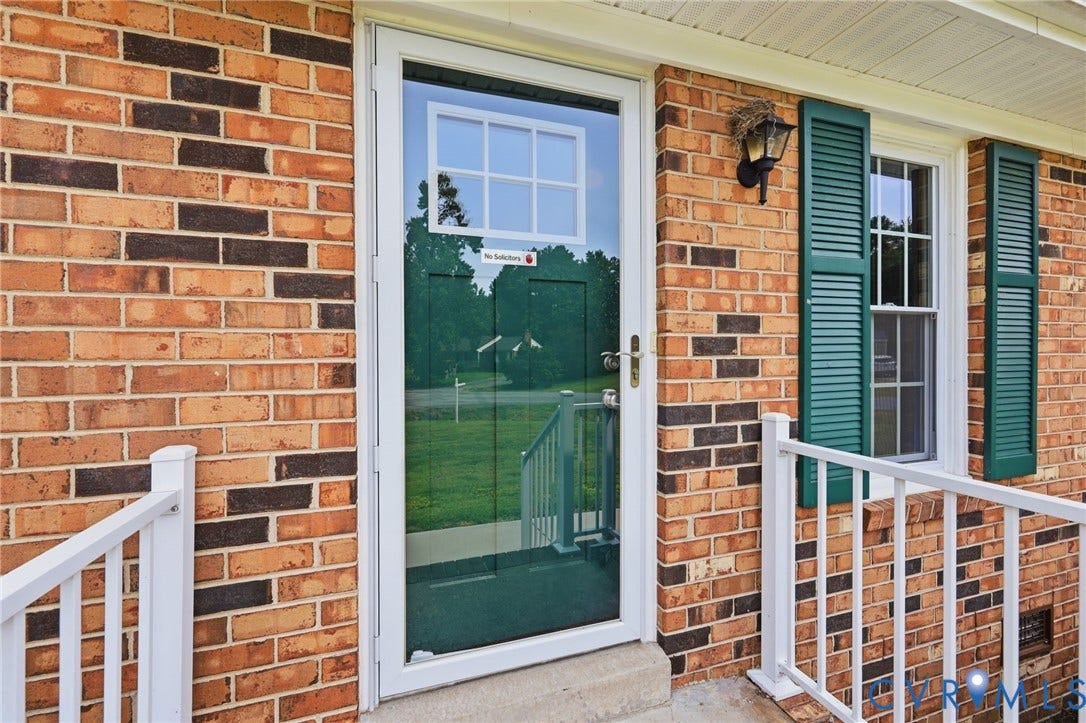 3221 Clintwood Road, Midlothian, VA 23112 Brick exterior with white railing, green louvered shutters, and a storm door with window pane detailing