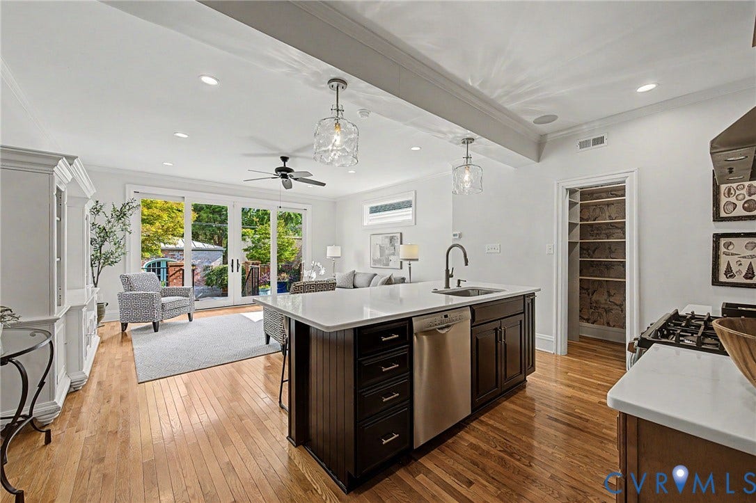 Open-concept kitchen and living area featuring wood-finish flooring, recessed lighting, and a kitchen island with a built-in sink and dishwasher