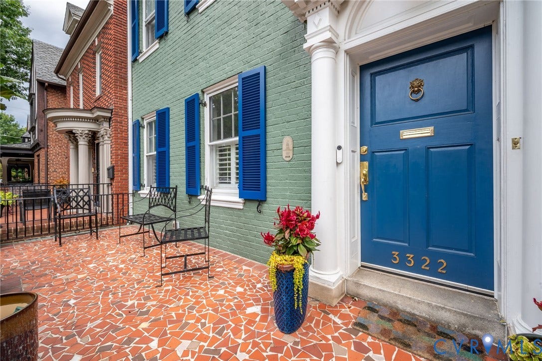 Brick facade with blue louvered shutters, complemented by a mosaic tile patio