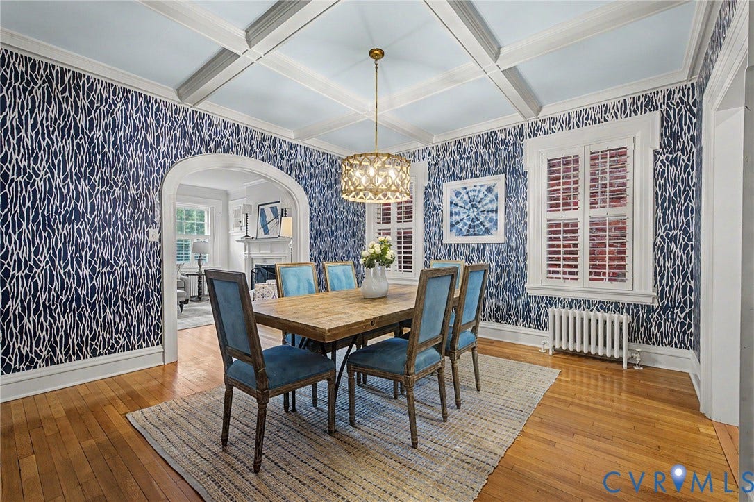 Hardwood flooring, coffered ceiling, archway, decorative pendant light fixture, and window with plantation shutters