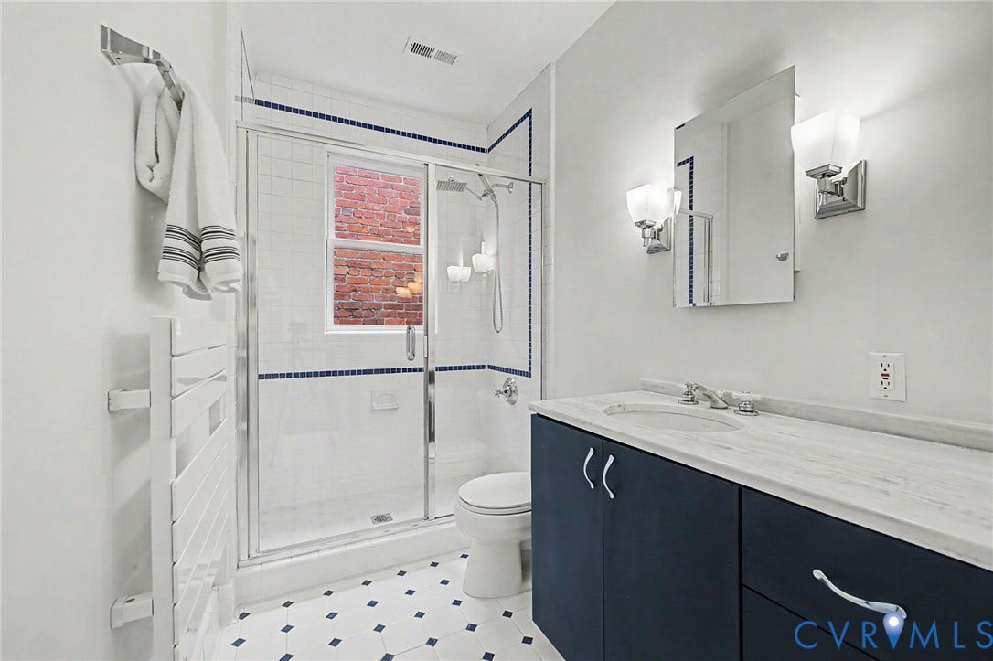 Vanity with a light-colored countertop, dark blue cabinetry, and a rectangular mirror with sconce lighting