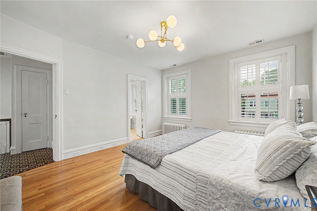 Hardwood flooring, two windows with plantation shutters, contemporary chandelier, and white wall finishes