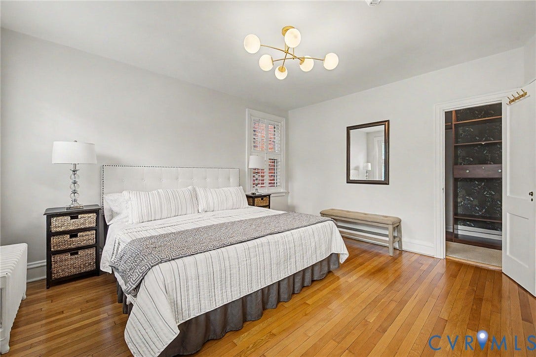 Hardwood flooring, recessed window with plantation shutters, ceiling-mounted light fixture, built-in closet system, and a solid core door