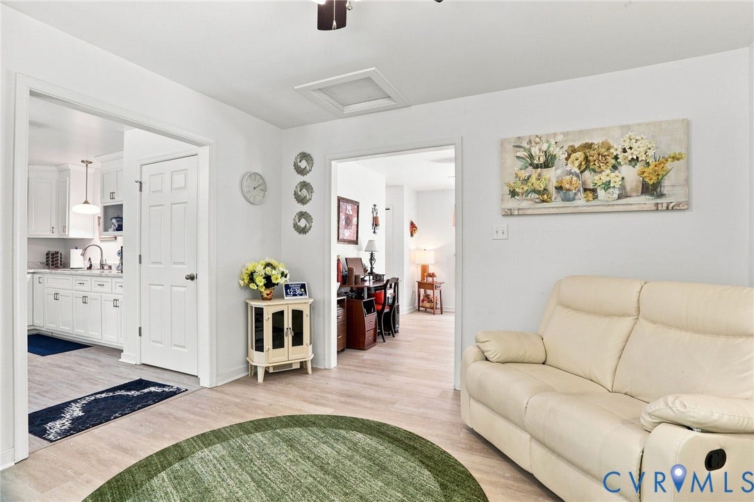 4512 Forrestal Road, Chester, VA 23831 Bright, open-concept living area featuring wood-finish flooring throughout, a curved green area rug, and a cream-colored reclining sofa