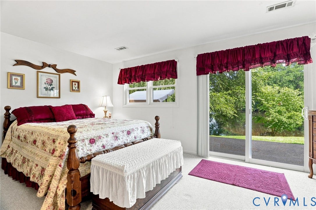 4512 Forrestal Road, Chester, VA 23831 Primary Bedroom Suite with Dual Windows, Glass Sliding Doors Opening to Grounds, Wood-Finish Four-Poster Bed Frame, Coordinated Burgundy Window Treatments with Valances, and Upholstered Bench at Foot of Bed