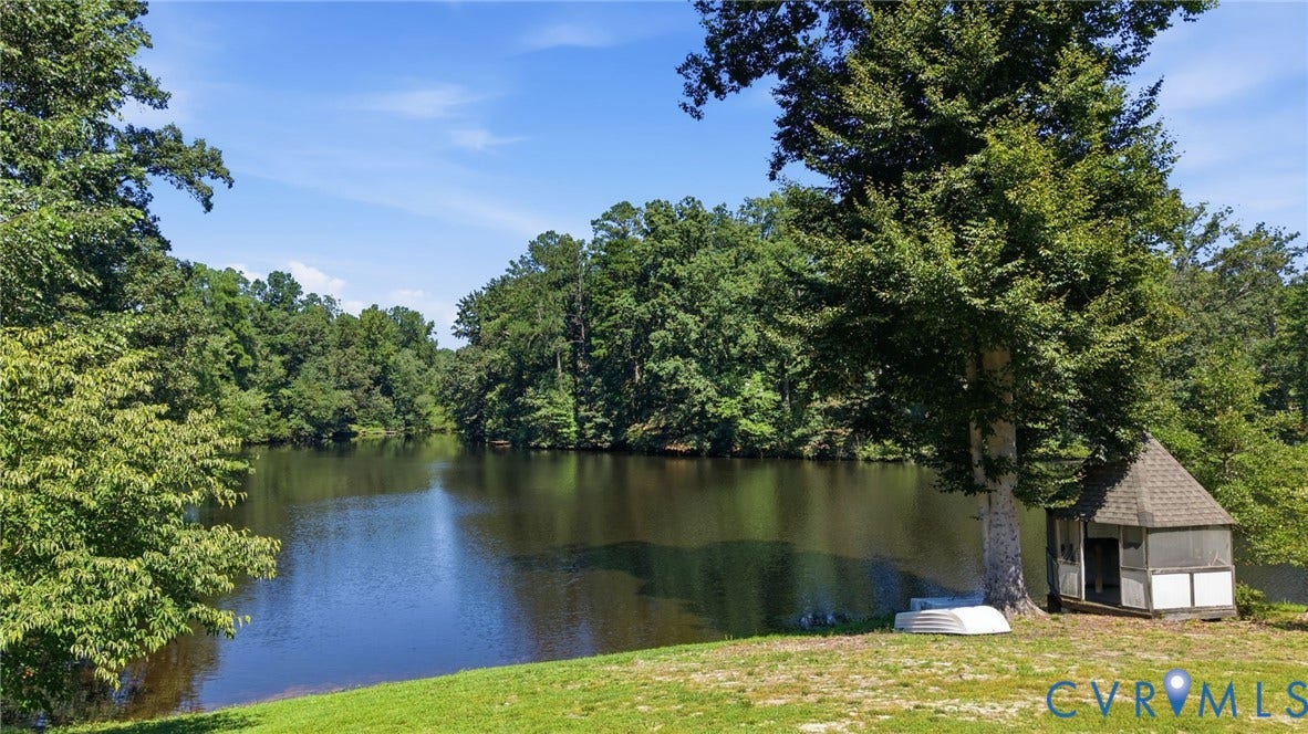 4512 Forrestal Road, Chester, VA 23831 Waterfront property featuring a serene pond bordered by mature shade trees and lush landscaping