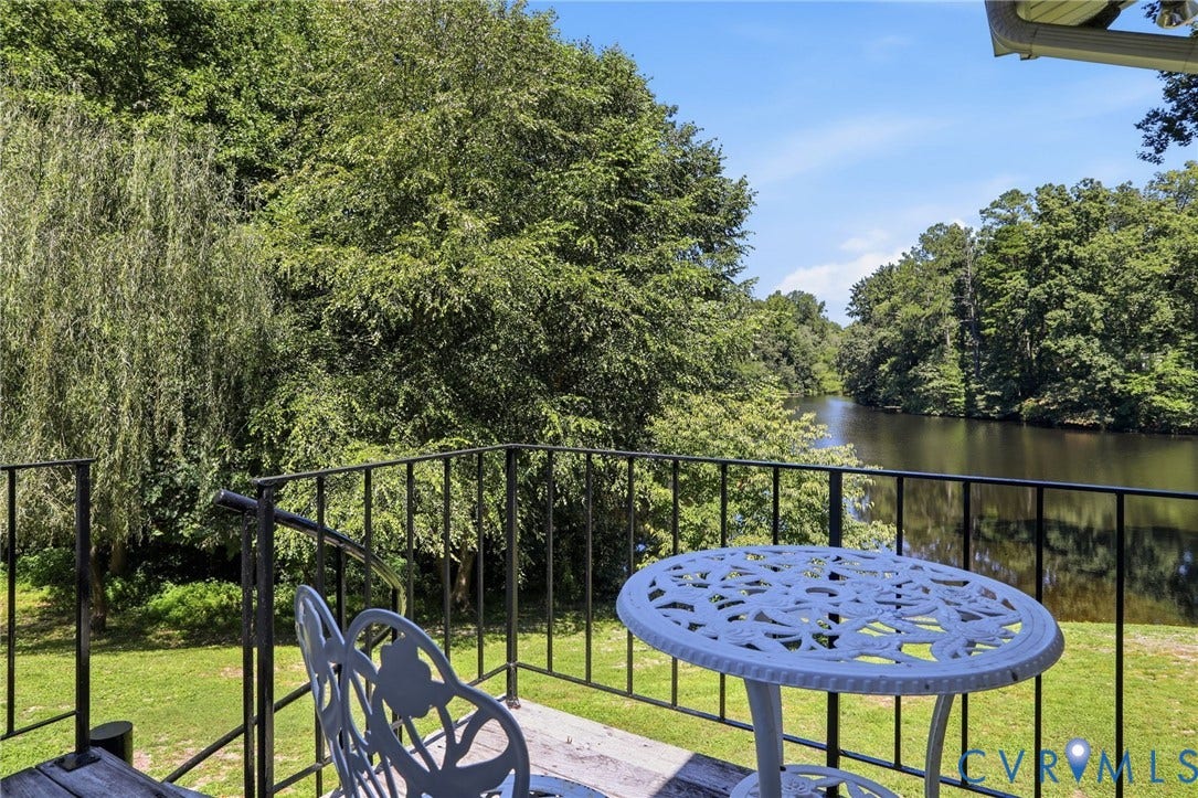 4512 Forrestal Road, Chester, VA 23831 Balcony with black metal railings overlooking a body of water, surrounded by mature trees and a grassy area