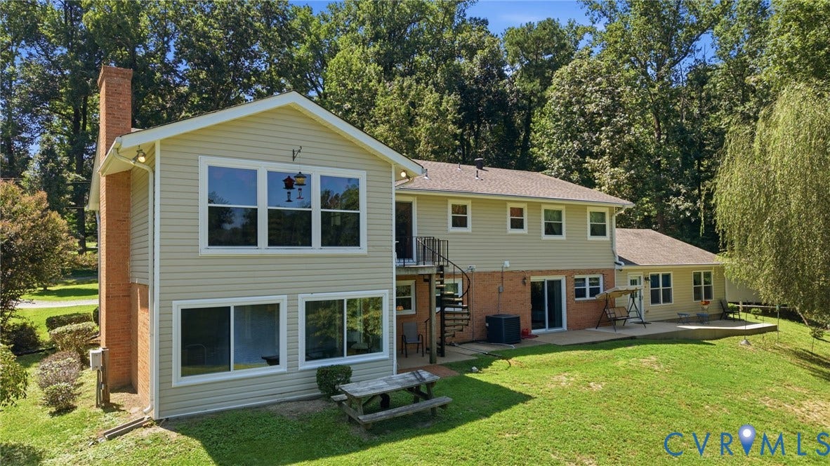 4512 Forrestal Road, Chester, VA 23831 Contemporary split-level residence featuring a brick and vinyl exterior with expansive windows, multi-level deck access, and a manicured lawn bordered by mature landscaping