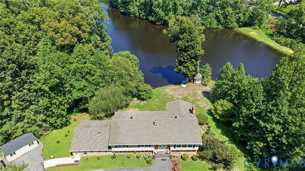4512 Forrestal Road, Chester, VA 23831 Waterfront property featuring a single-story residence with a gray shingle roof, extensive green landscaping, and mature trees