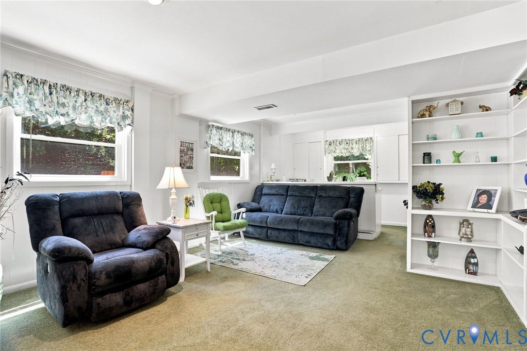 4512 Forrestal Road, Chester, VA 23831 Bright and spacious living area featuring multiple windows with natural light, neutral carpet flooring, and built-in white cabinetry with display shelving