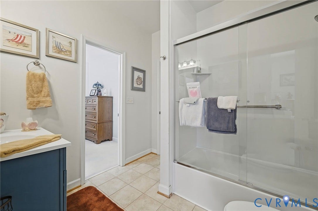 1577 Moody Town Road, Bumpass, VA 23024 Shower-tub combination with sliding glass doors, vanity with a blue cabinet, and tile flooring