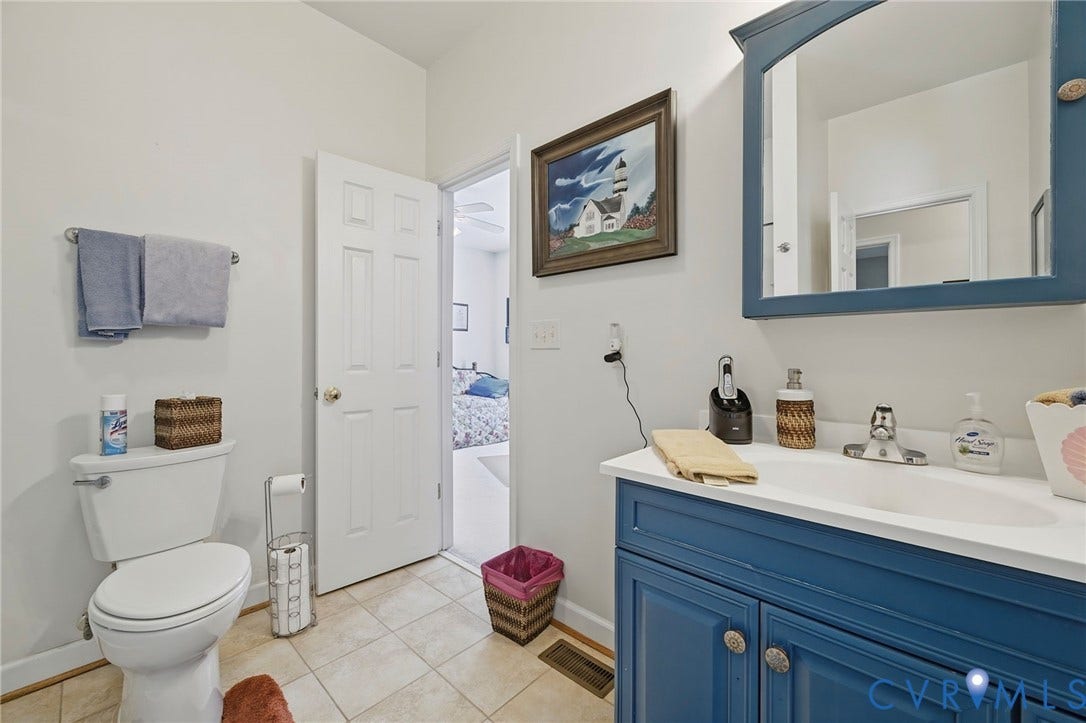 1577 Moody Town Road, Bumpass, VA 23024 White vanity countertop with an integrated sink, blue wood-finish cabinet, and a coordinating blue framed mirror