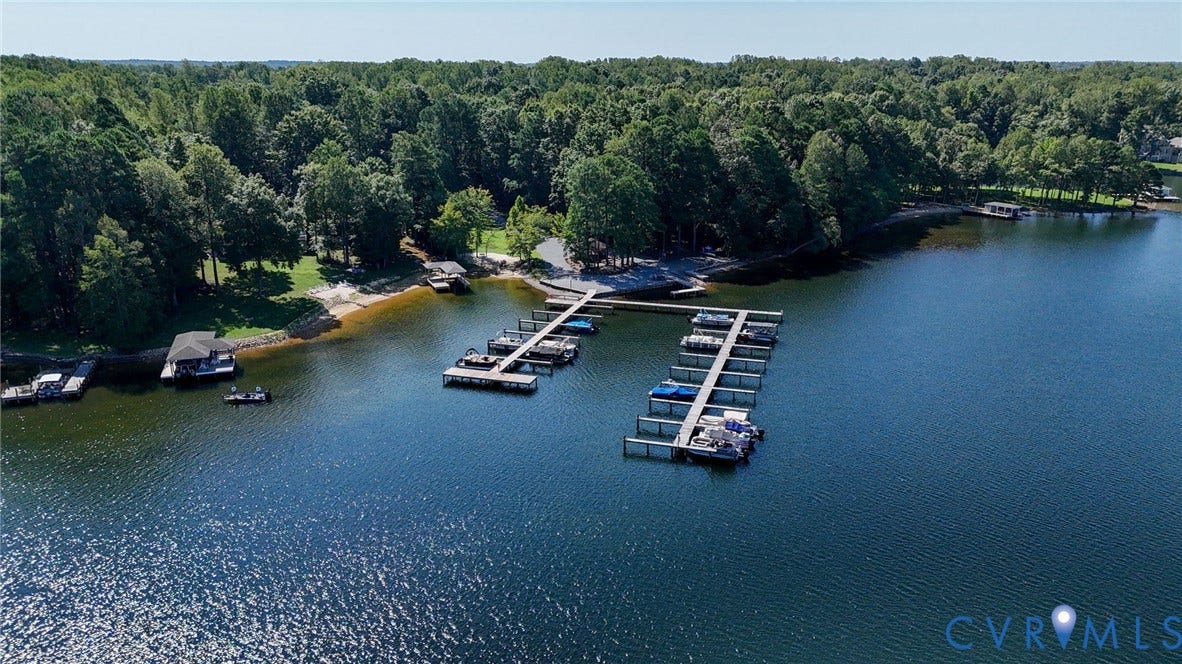 1577 Moody Town Road, Bumpass, VA 23024 Lakefront property featuring a wooded shoreline, private sandy beach area, multiple boat docks, and a boat house