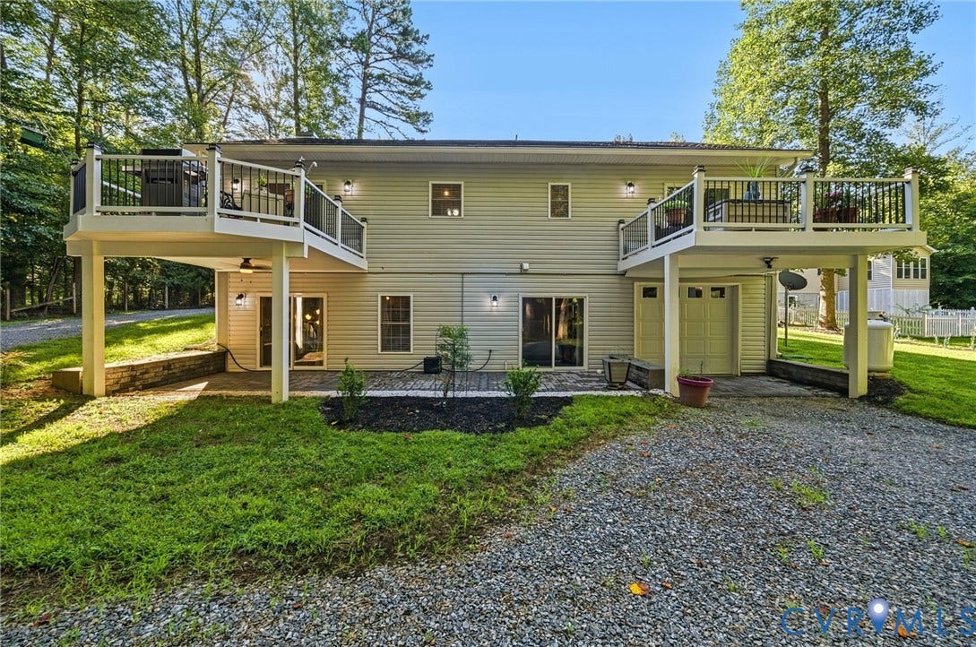 1577 Moody Town Road, Bumpass, VA 23024 Dual elevated decks, light-colored siding, multiple glass-paneled doors, ground-level patios, and gravel driveway
