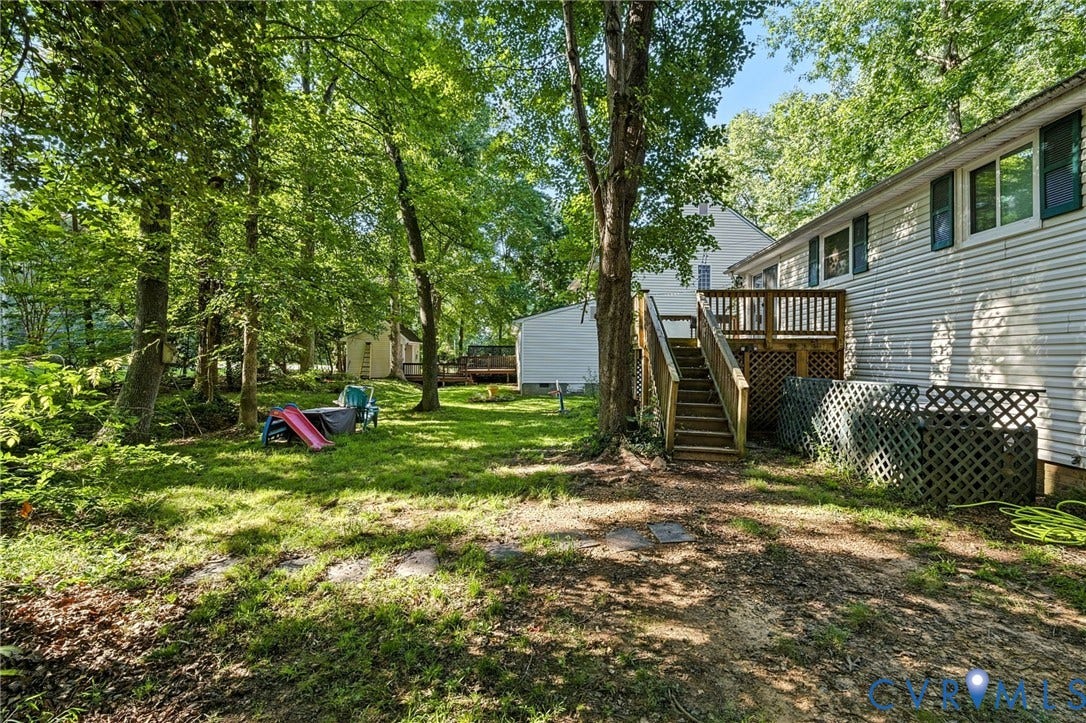 2709 Sutters Mill Court, Midlothian, VA 23112 Wood deck with railing and stairs, siding exterior, multiple windows with shutters, mature trees, and a grassy lawn
