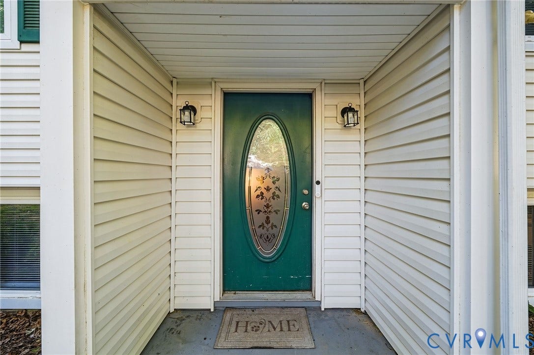 2709 Sutters Mill Court, Midlothian, VA 23112 Welcoming entry featuring a distinctive oval glass-panel door in forest green, flanking sidelights with decorative sconces, horizontal lap siding in cream, and a covered portico with coffered ceiling detail