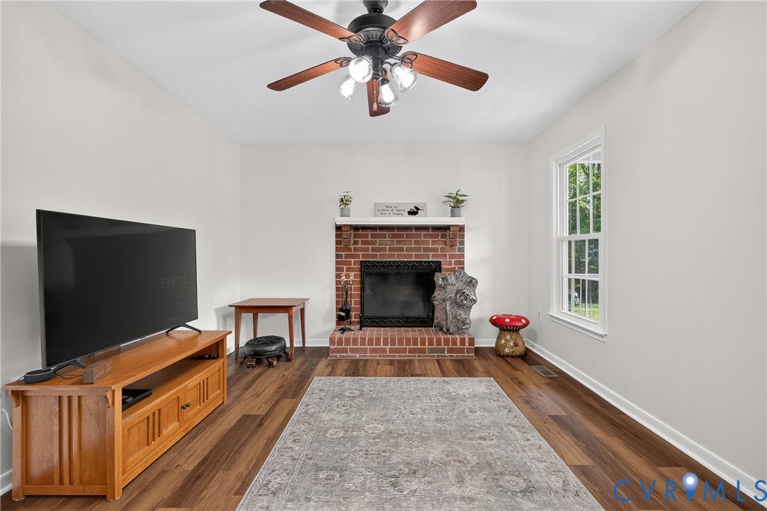 7248 Full Rack Drive, Midlothian, VA 23112 Vaulted ceiling with a ceiling fan, brick fireplace, wood-finish flooring, and a double-hung window