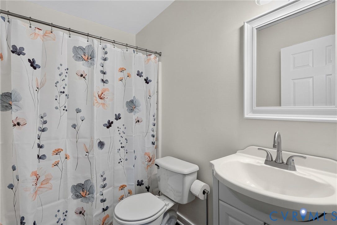 7248 Full Rack Drive, Midlothian, VA 23112 White vanity with an integrated sink and brushed nickel faucet, a white framed mirror, and a white toilet