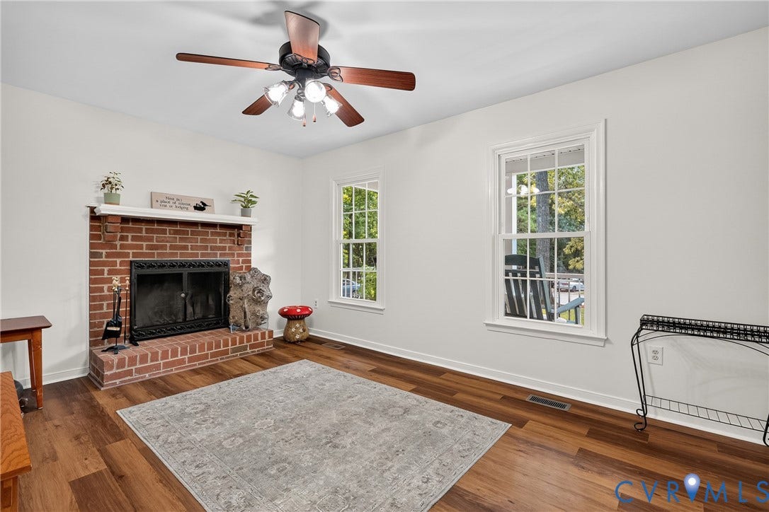 7248 Full Rack Drive, Midlothian, VA 23112 Brick fireplace with a white mantel, wood-finish flooring, white walls, and a ceiling fan with integrated lighting