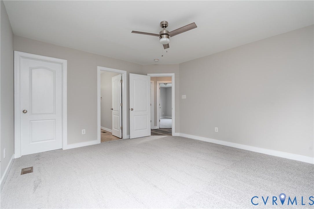 Neutral wall tones, light gray carpeting, and a ceiling fan with integrated lighting