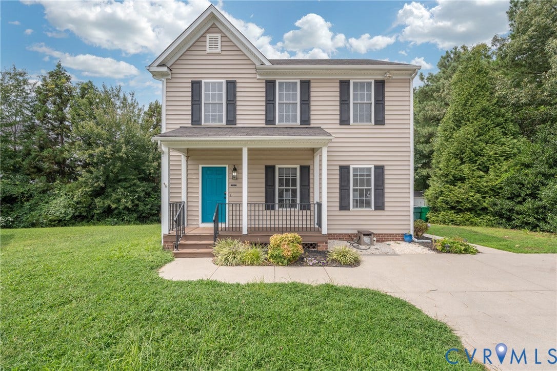 Two-story residential exterior with light-colored siding, a covered front porch, and a bright blue entry door